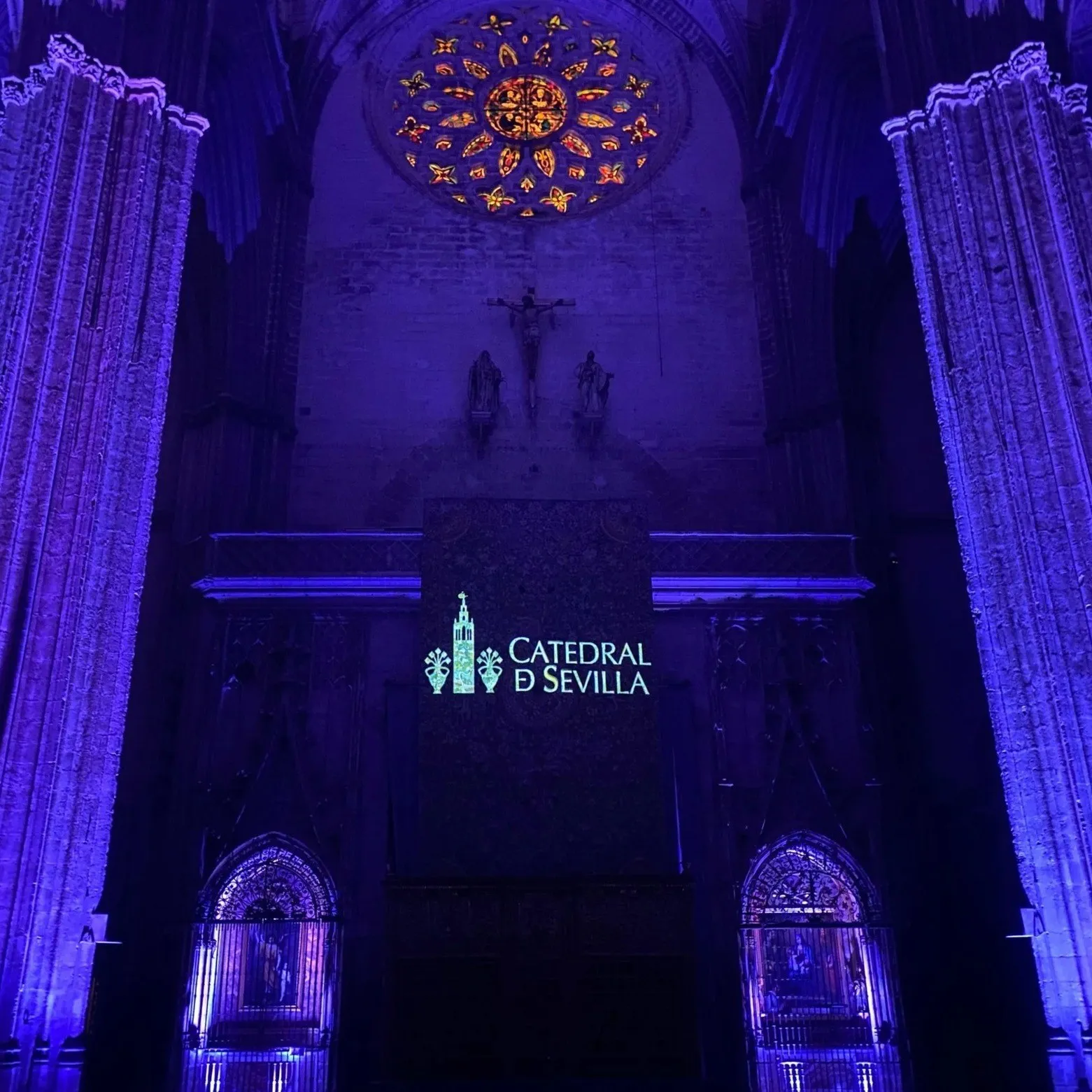 Fachada interior de la Catedral de Sevilla iluminada de azul con el logotipo de la Catedral proyectado