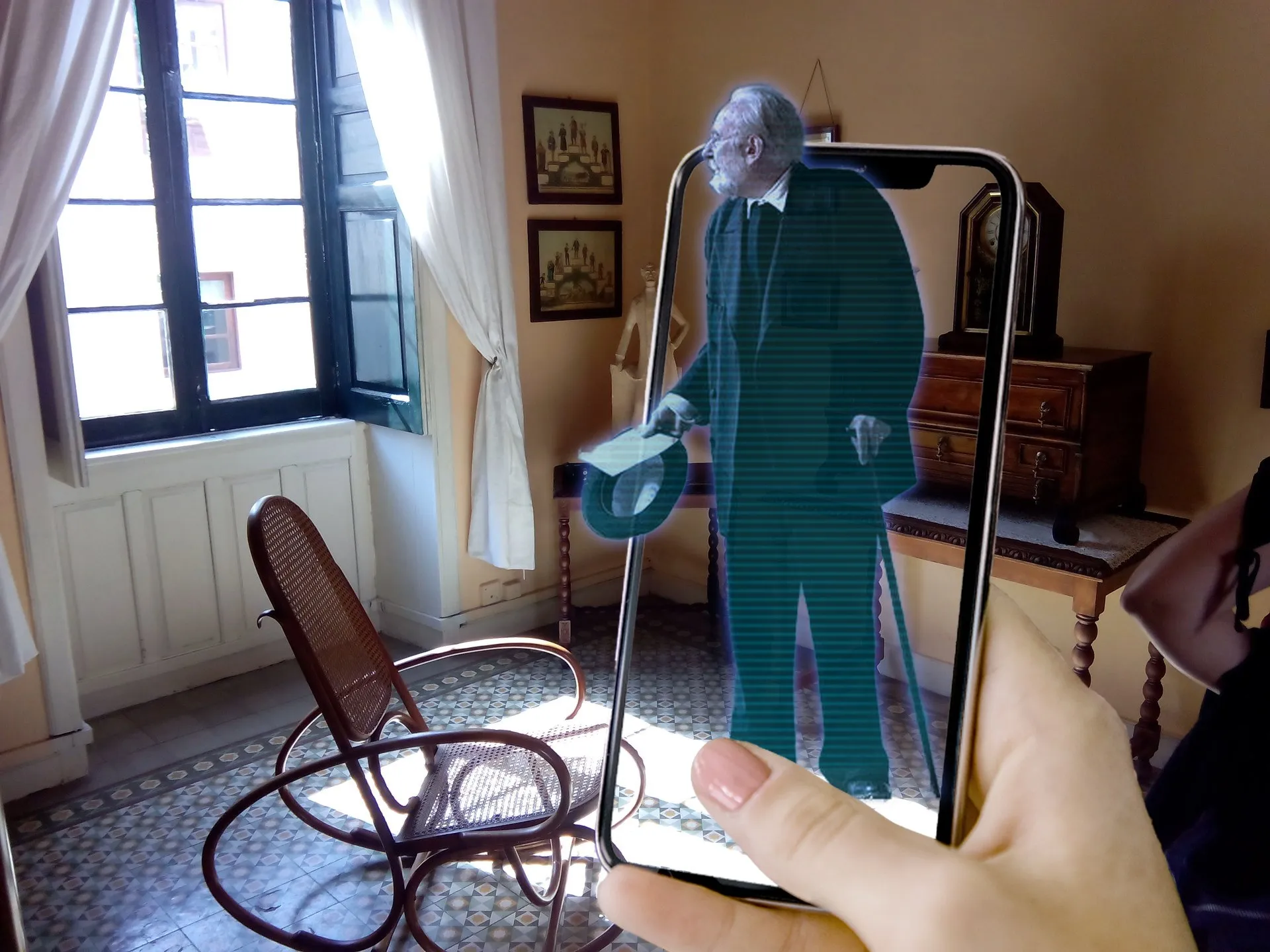 Holograma de Miguel de Unamuno con sombrero en la mano visto a través de un móvil en su casa museo