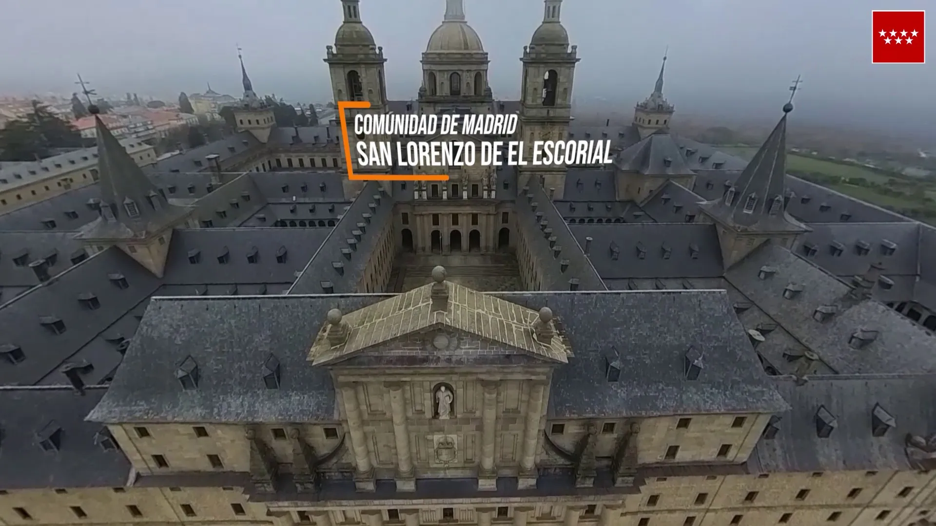 Monasterio de El Escorial desde el aire con el rótulo «Comunidad de Madrid, San Lorenzo de El Escorial»